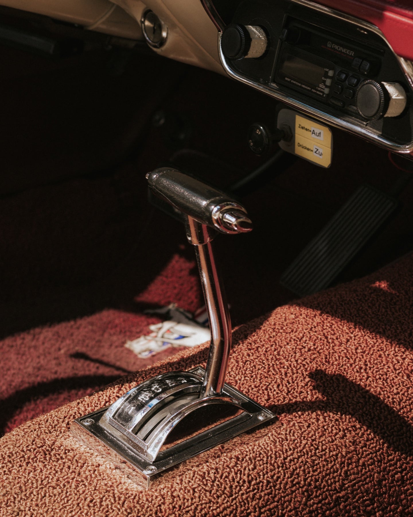Verchromter Hurst-Schalthebel im Innenraum eines Ford Mustang, dunkelroter Teppich und Pioneer-Radio