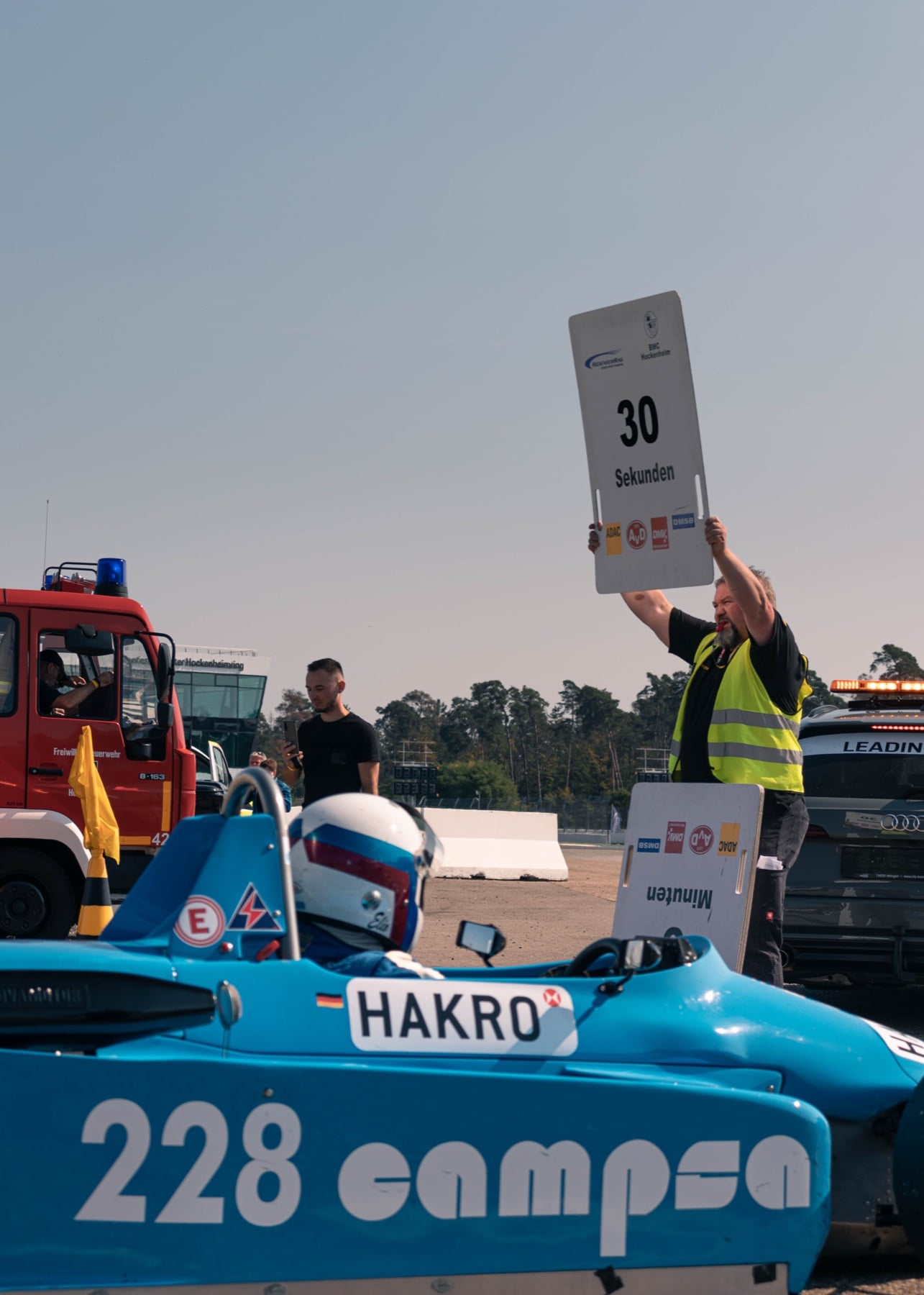 Streckenposten hält 30-Sekunden-Schild über einem blauen historischen Formel-Wagen am Start in Hockenheim