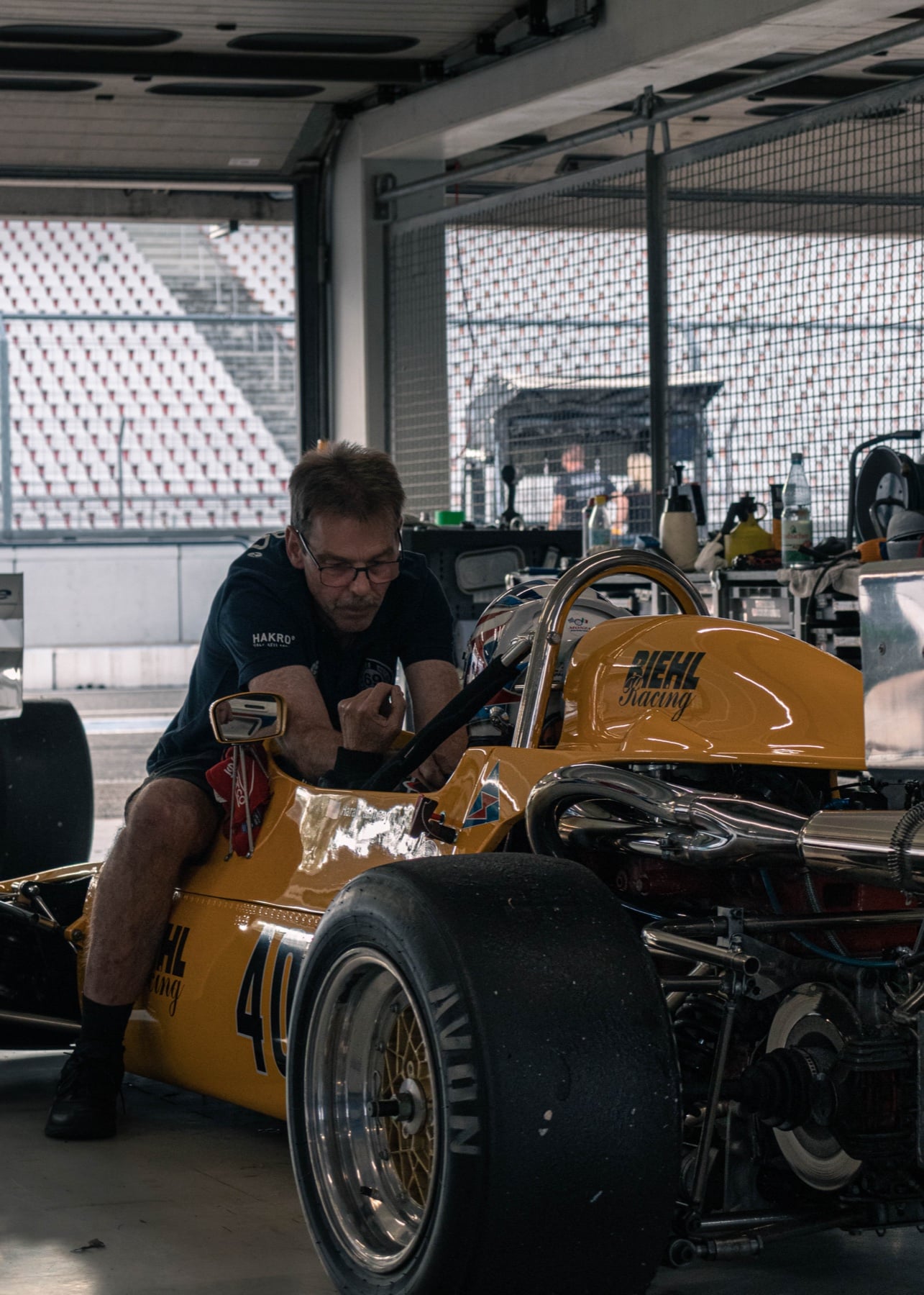 Mechaniker beim Schrauben am gelben Vintage-Formel-Wagen mit Startnummer 401 in der Box von Hockenheim