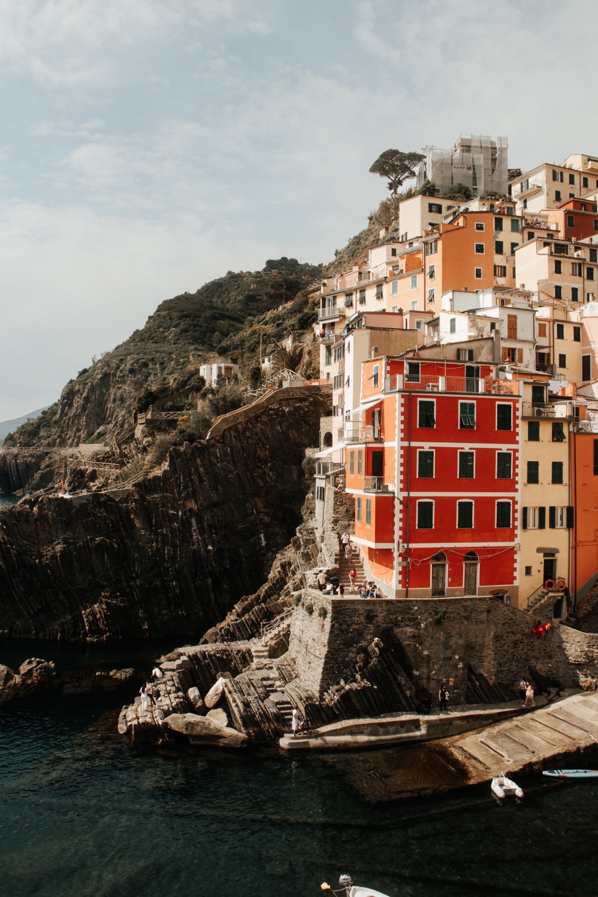 Rote Häuser von Riomaggiore an der Steilküste, Meer und Felsen im Vordergrund