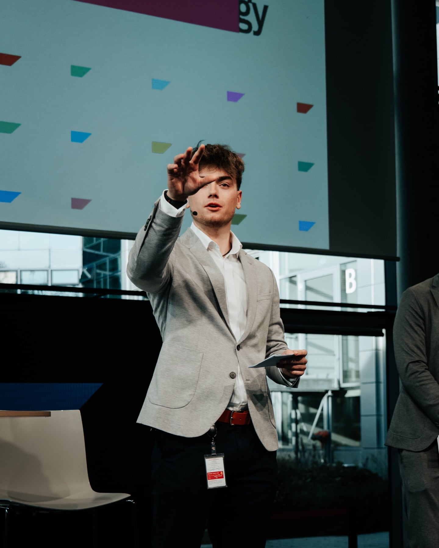 Junger Speaker mit Headset auf der Bühne von SAP nextGen, gestikulierend vor Hintergrundgrafik
