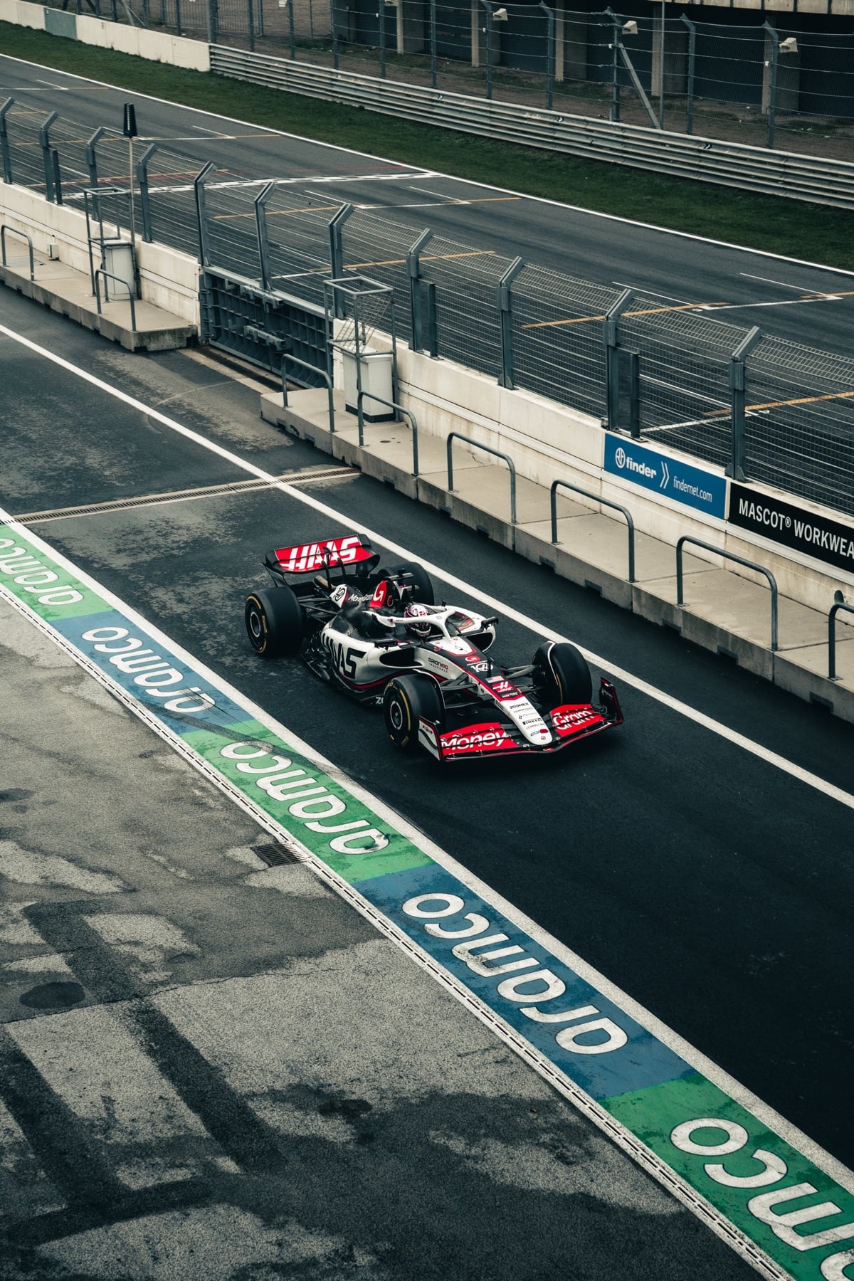 Aufsicht auf einen Haas-Formel-1-Wagen in der Box, daneben ein Mechaniker mit roter Jacke